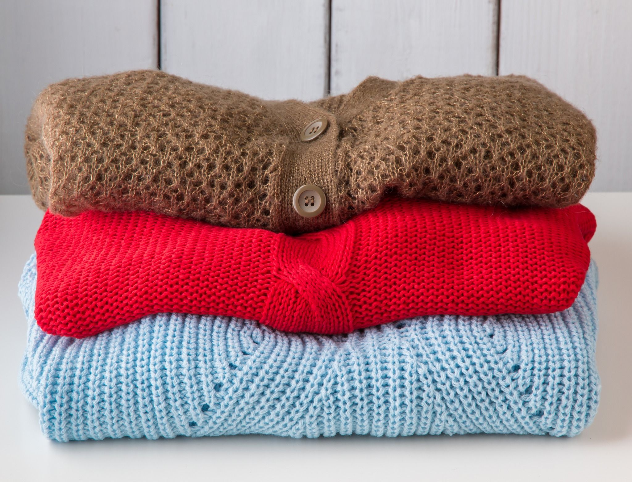 Stack of clean knitted sweaters and cardigans.