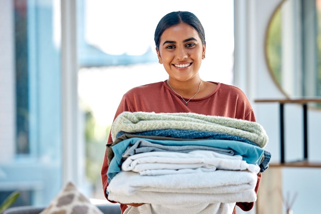 Smiling woman holding freshly folded laundry – Nashville laundry delivery service