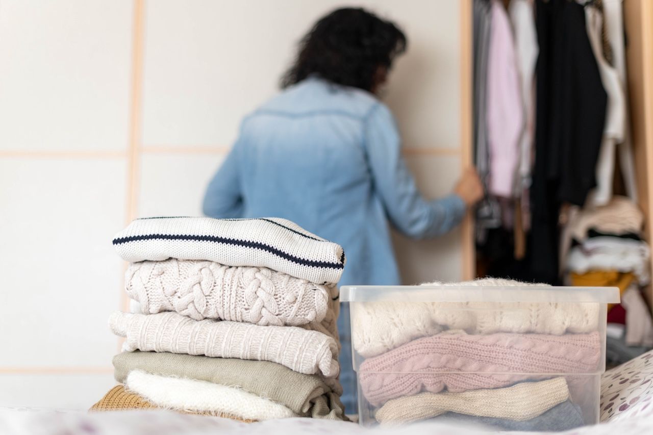 Pile of sweaters being put away in storage containers for spring