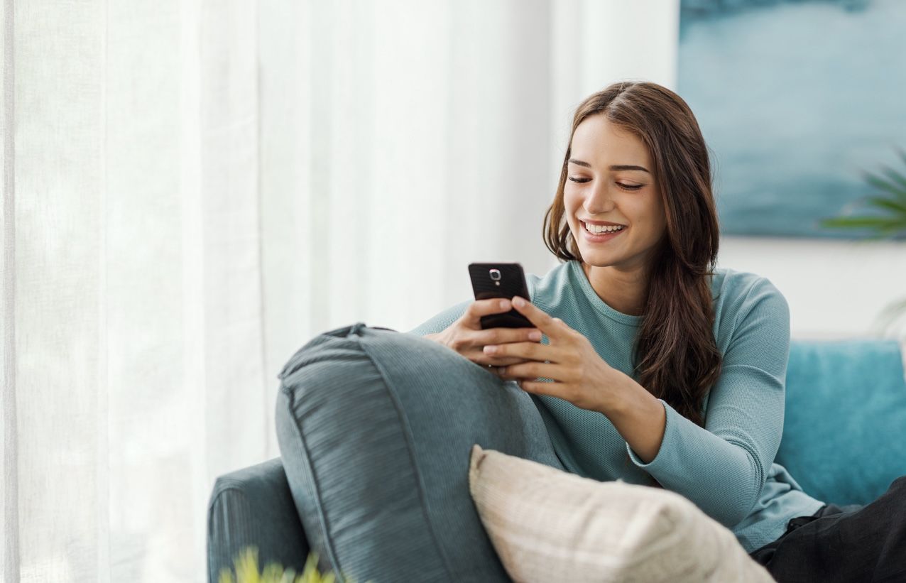 Woman using smartphone to schedule laundry pickup, showing the ease of laundry delivery service.