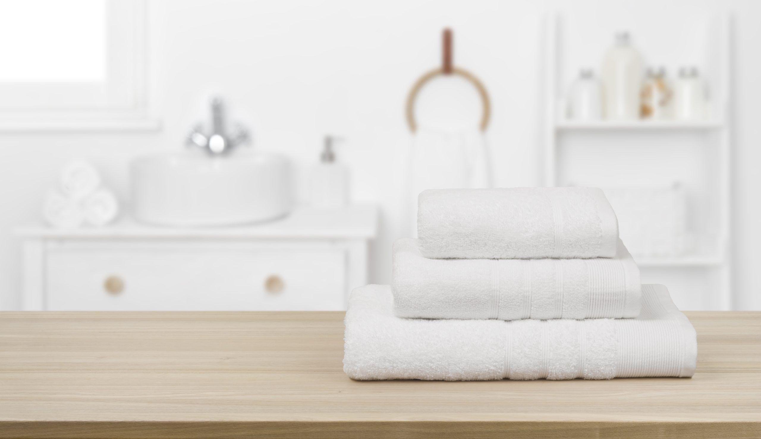 White towels folded nicely on counter, with bathroom in background