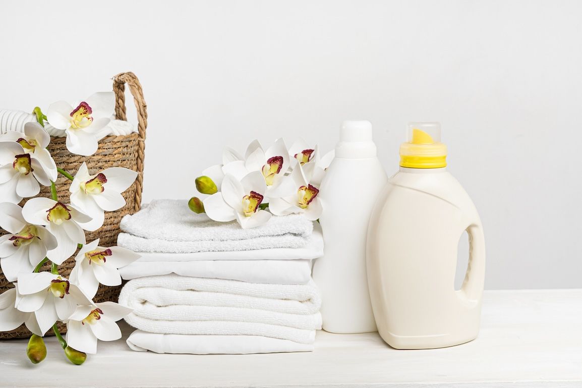 Freshly folded laundry next to detergent bottle. Spring flowers laying in laundry basket.